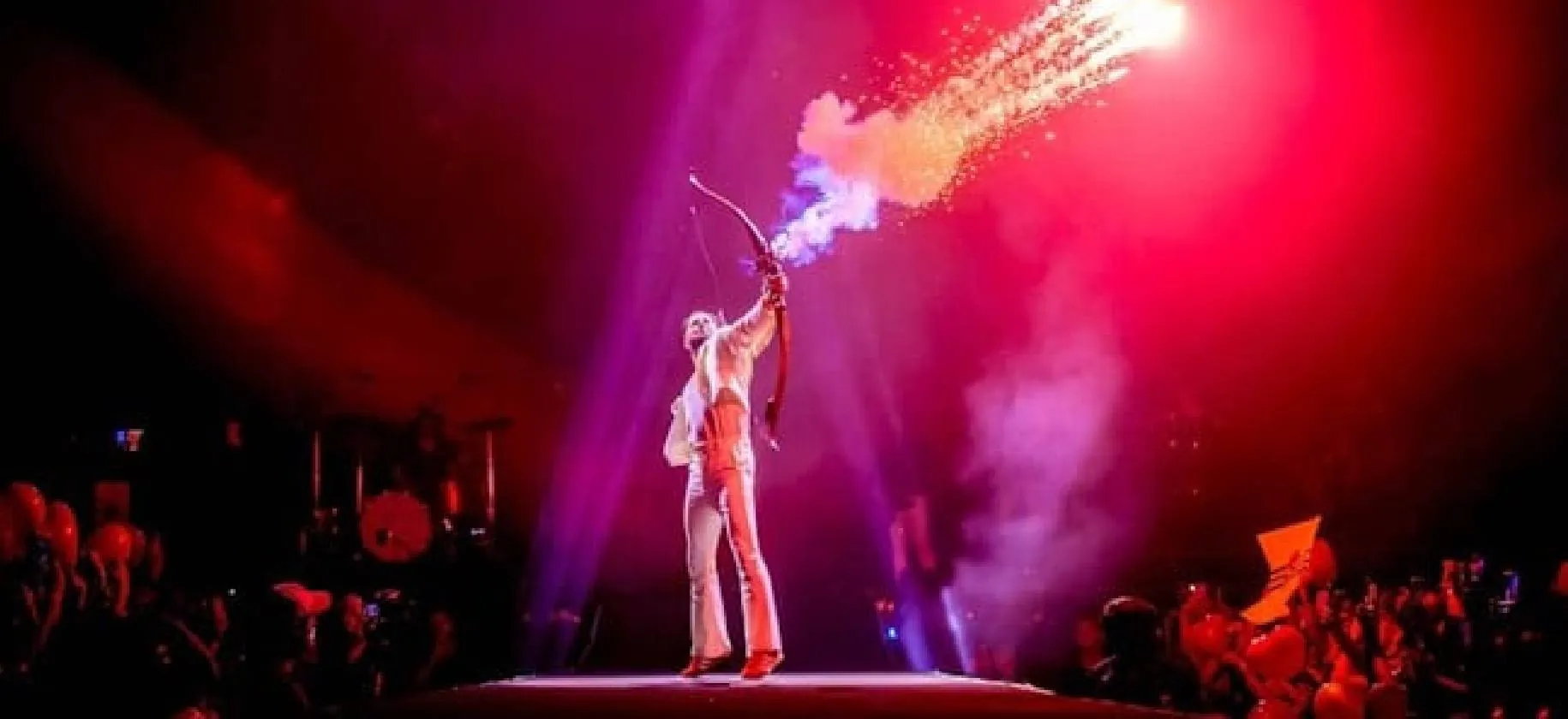 Manuel Carrasco dispara una flecha de humo desde el escenario, bajo una luz roja.